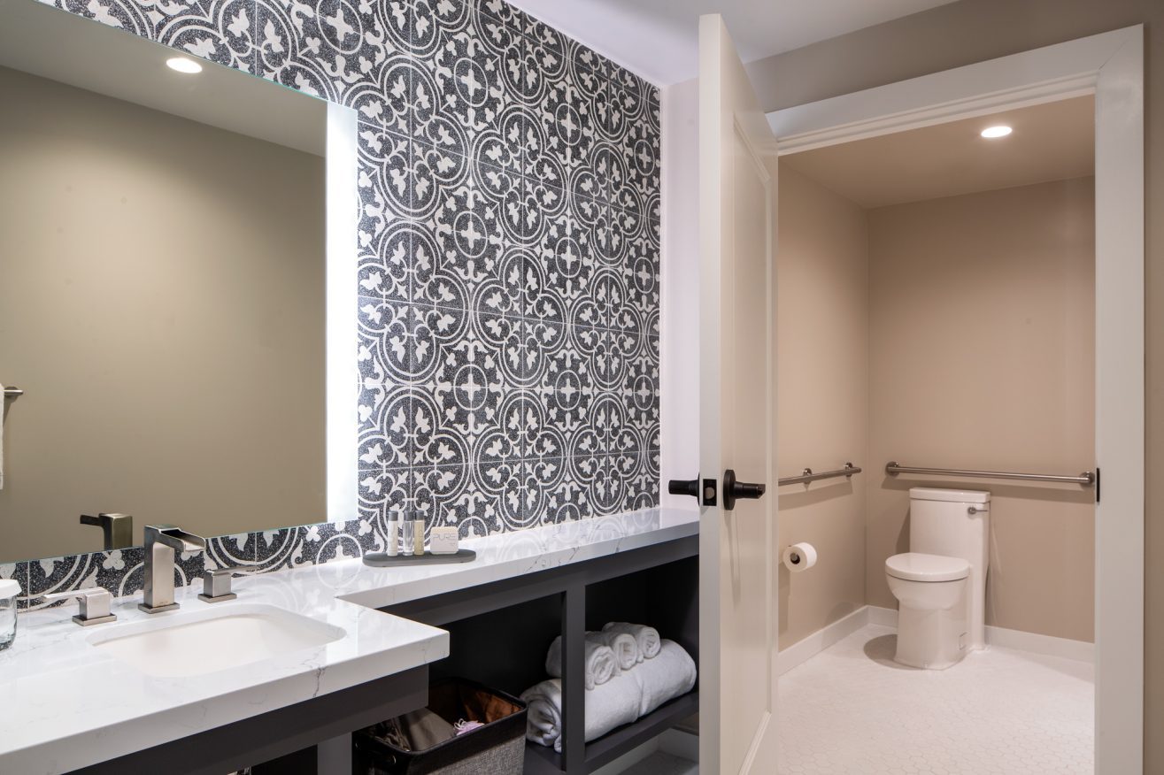 a Bathroom sink with tiles around the mirror and a shower.