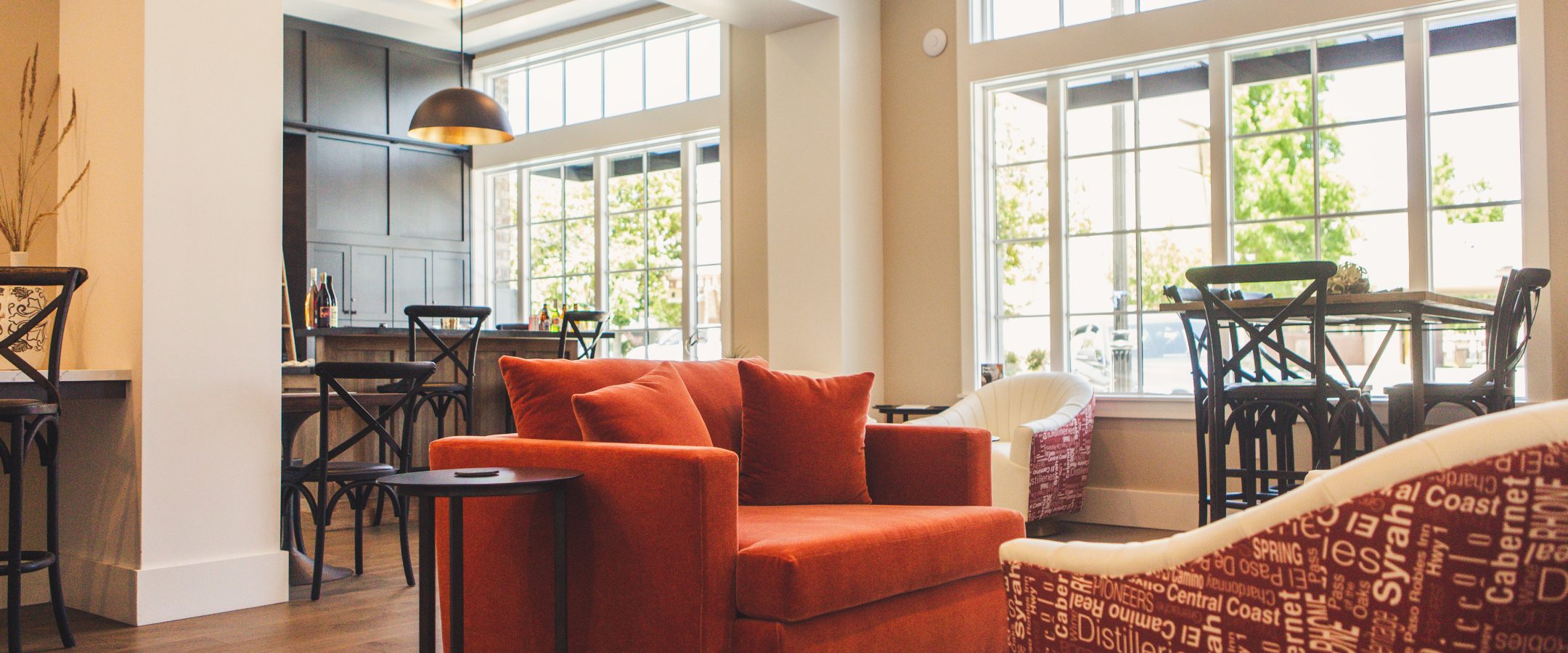 A lounge with a red sofa in a room with tall windows.