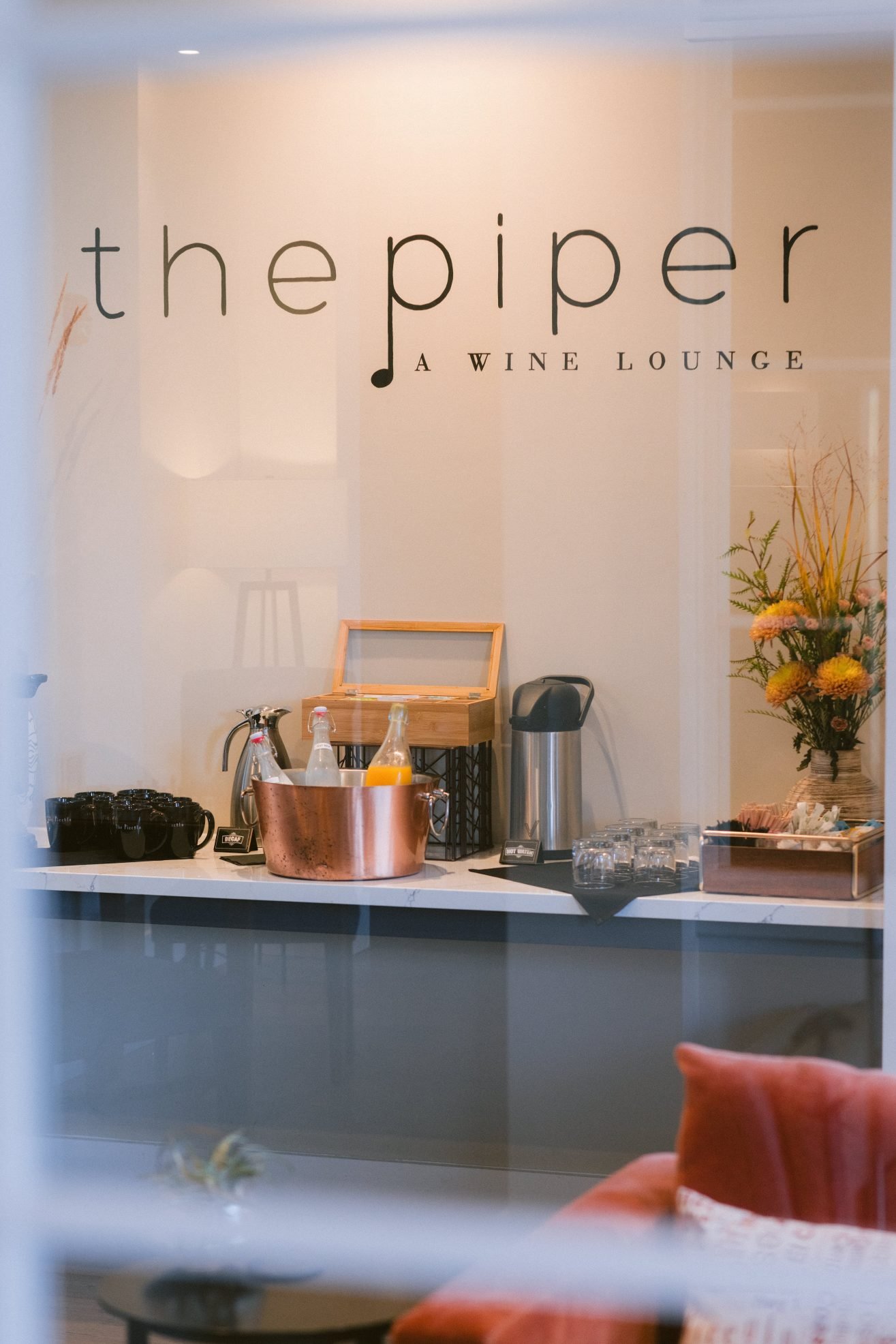 A coffee and mimosa station is set up on a sideboard. The Piper Wine Lounge sign is above it.