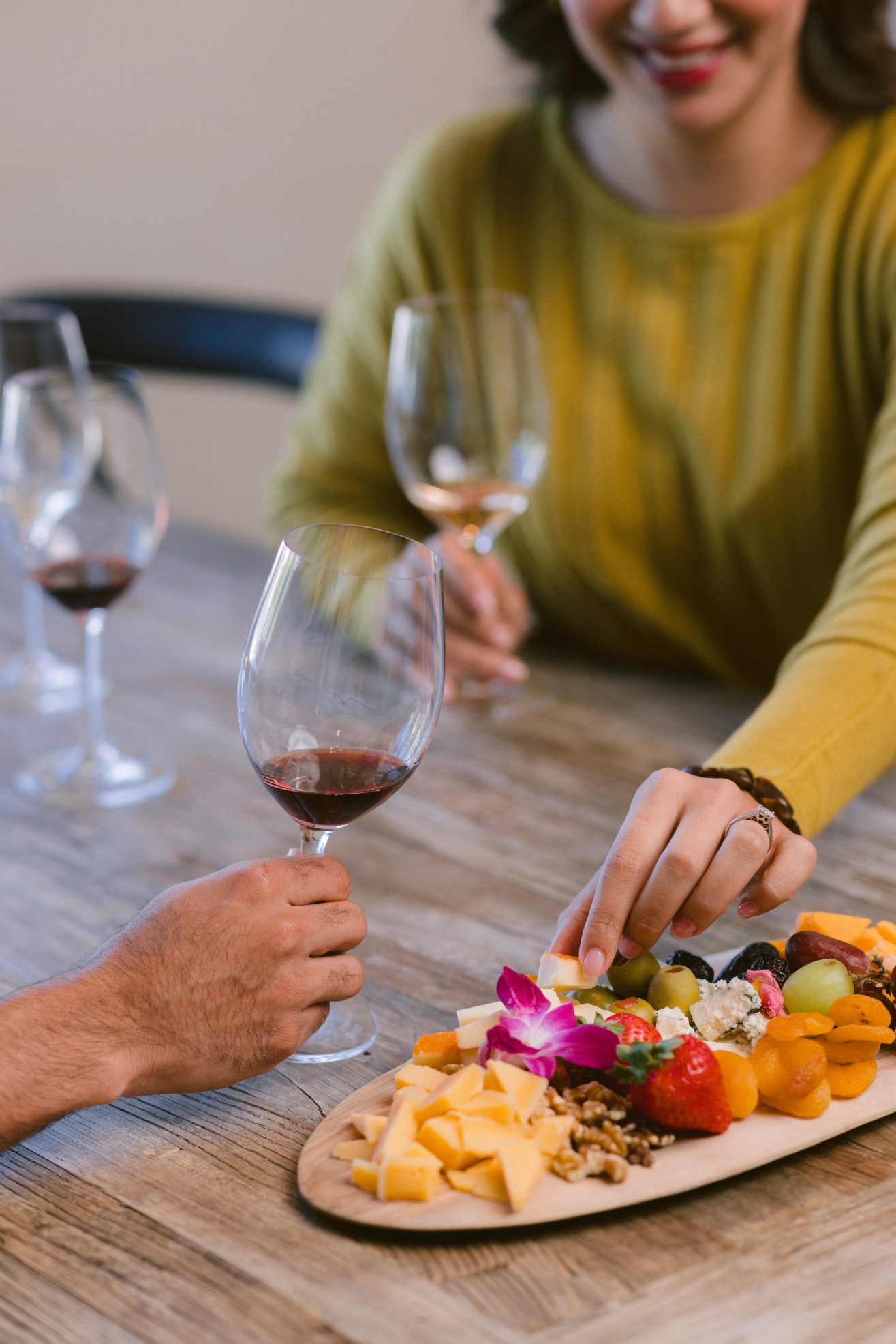 People wine tasting and a woman reaching for a piece of cheese