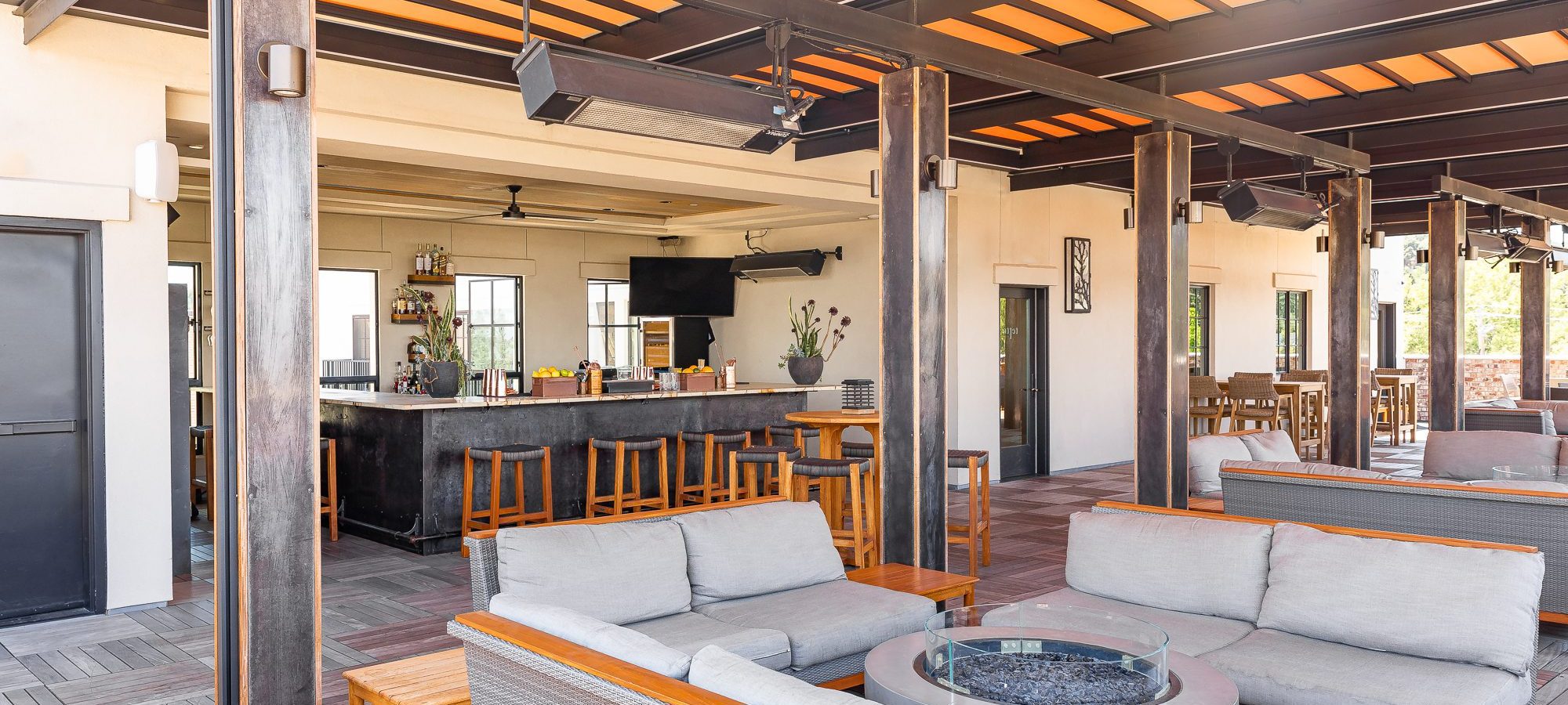 A roof top bar with sofas around a fire pit