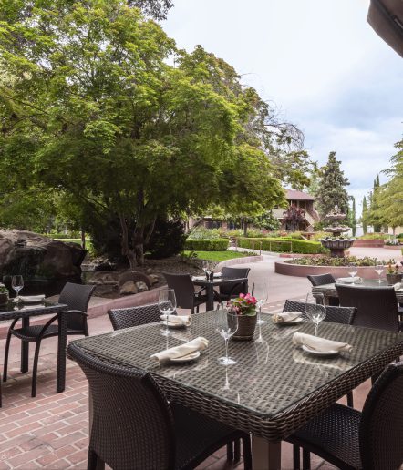 Outdoor seating with square tables and four chairs at each table located in a courtyard.