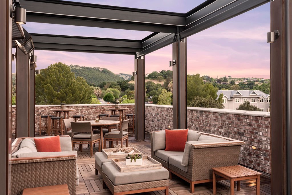 Stylish seating arranged around a rectangular table, located on an open air rooftop.