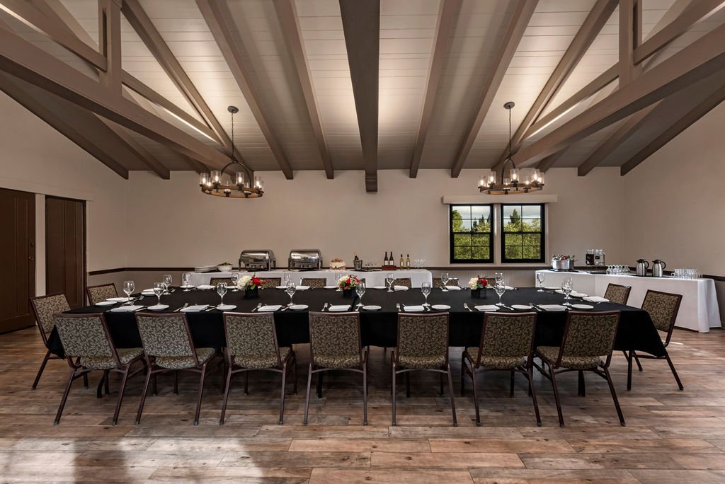 A private dinner table with black colored linens and dishes and silverware placed in front of each seat.