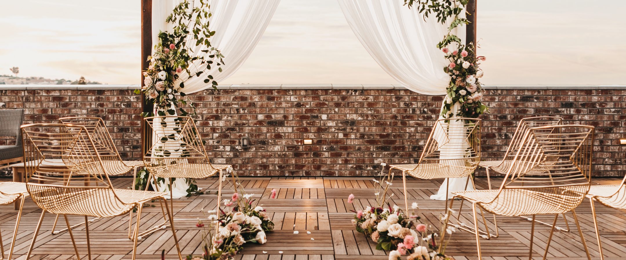 A rooftop alter adorned with floral arrangements and white sheets.