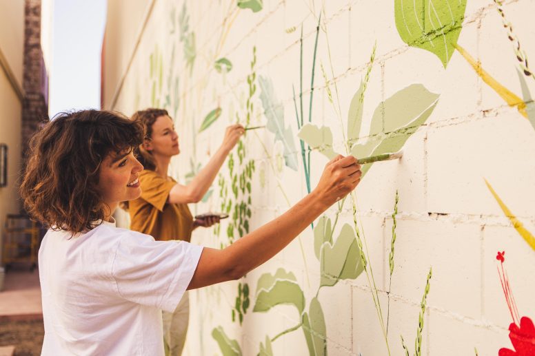 Two woman painting a floral mural